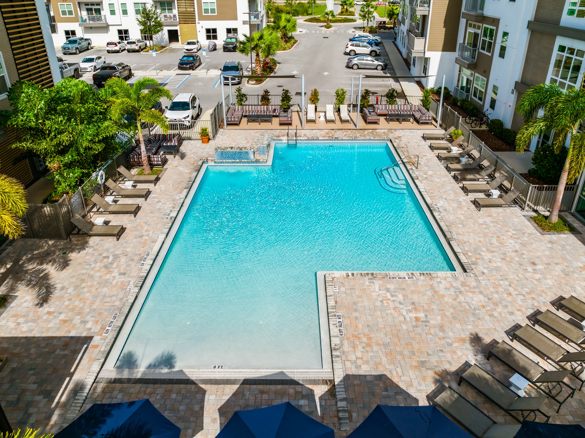 A swimming pool surrounded by lounge chairs and umbrellas.